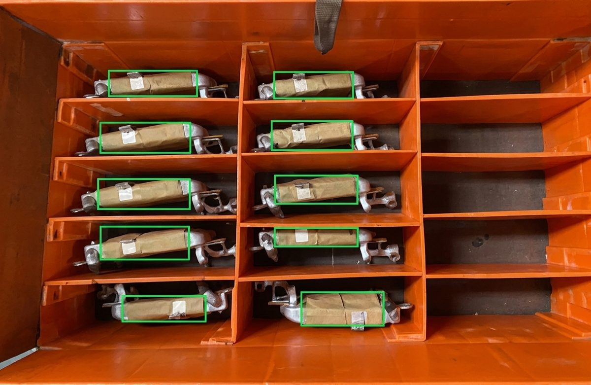 Parts detected in each compartment of a divided orange tote, with per-cell bounding boxes.